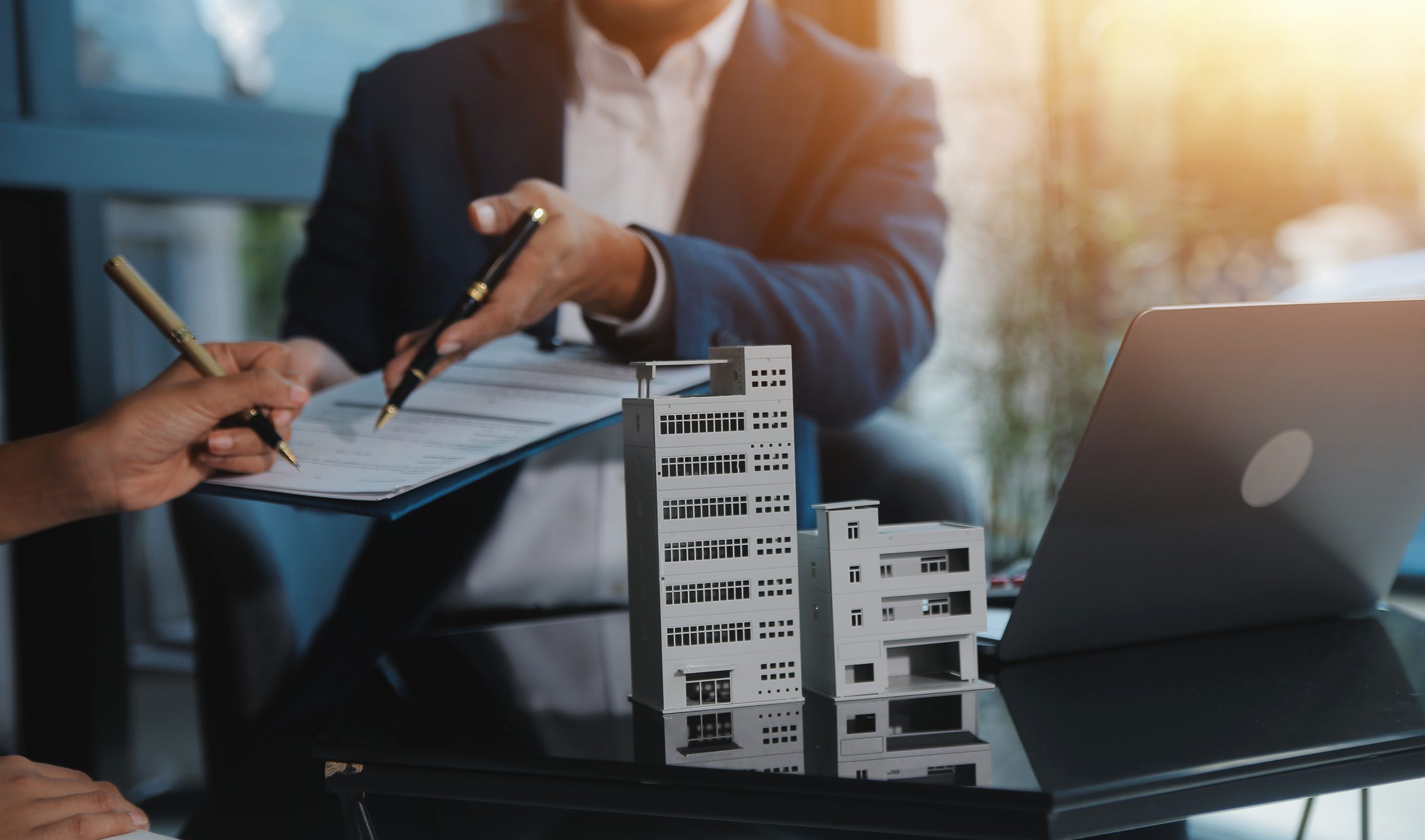 Real estate signing with building model.