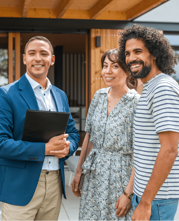Real estate agent with happy couple outside.
